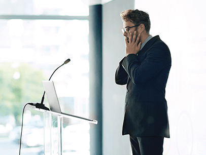 Nervous man standing at lectern with laptop 